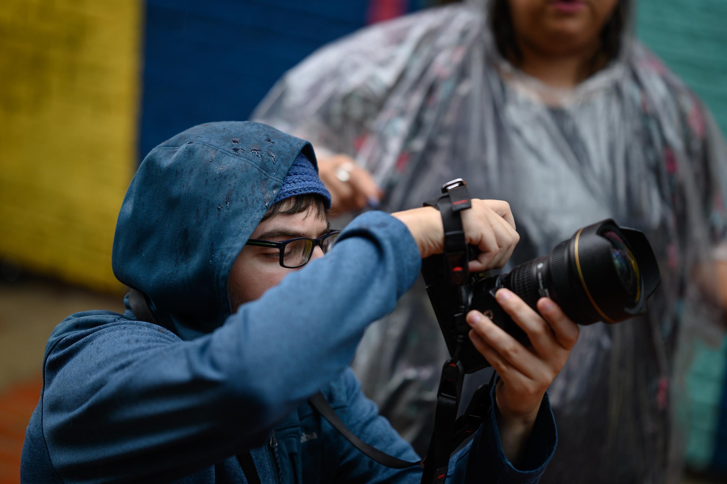 Photography student holding a camera with supervisor in background